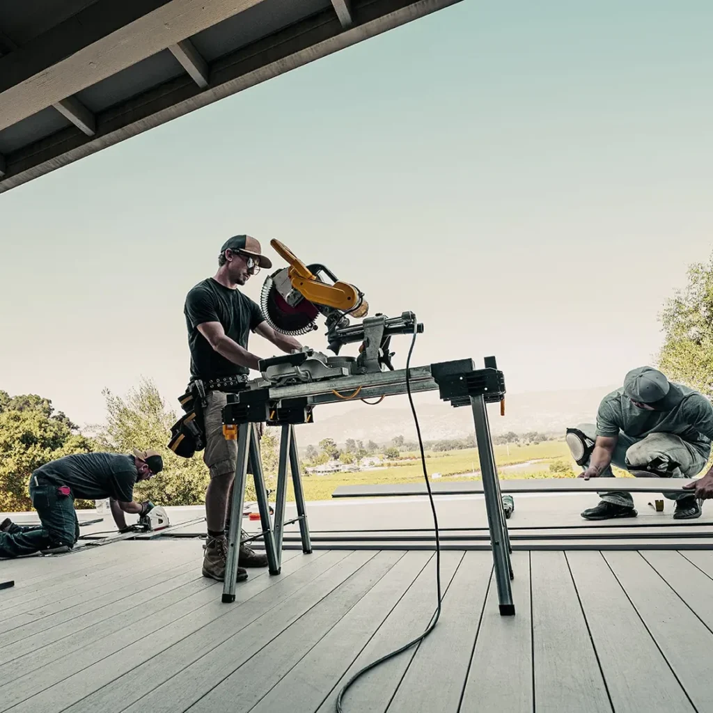 Deck crew installing TimberTech composite decking with power tools, upgrading an outdoor living space.