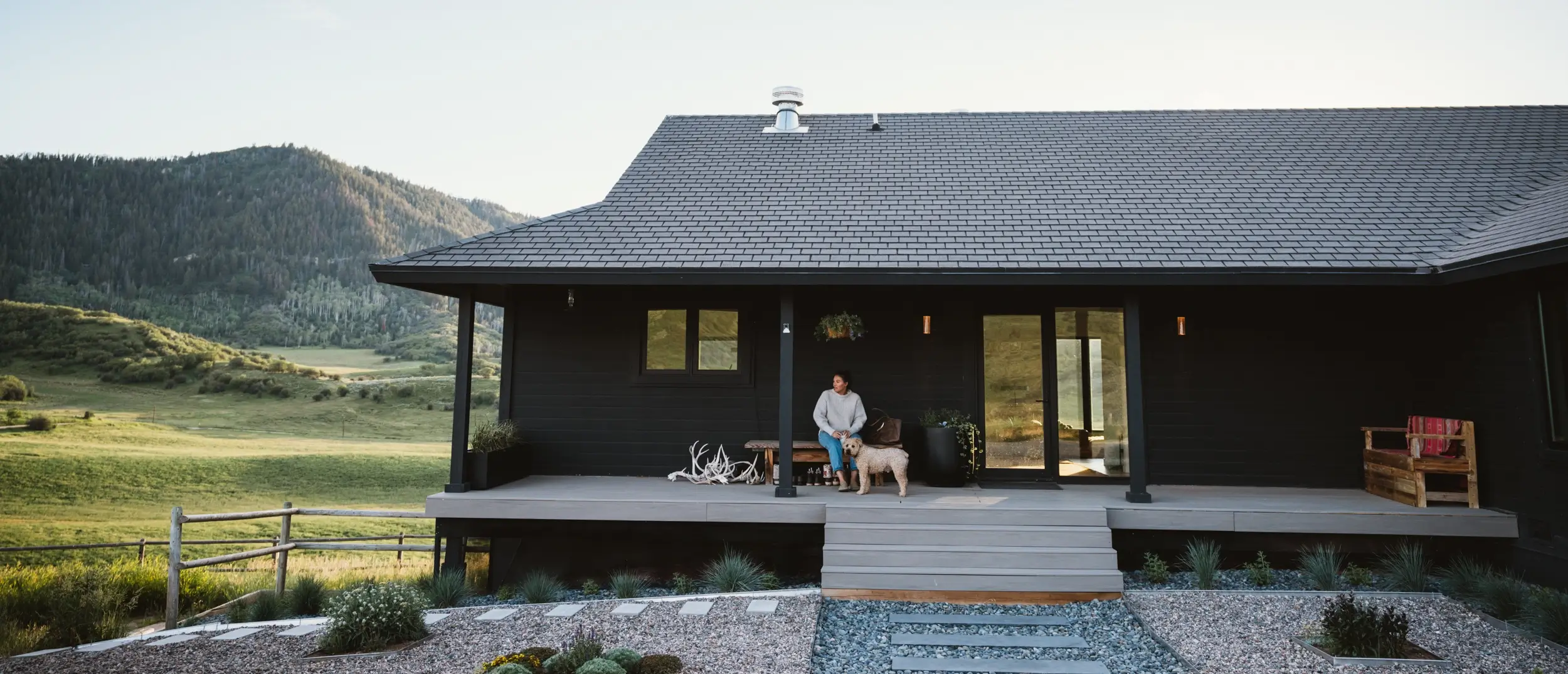 Modern TimberTech Coastline composite deck with two lounge chairs overlooking rolling green hills and mountains, built by Lifetime Home Remodeling in Colorado.